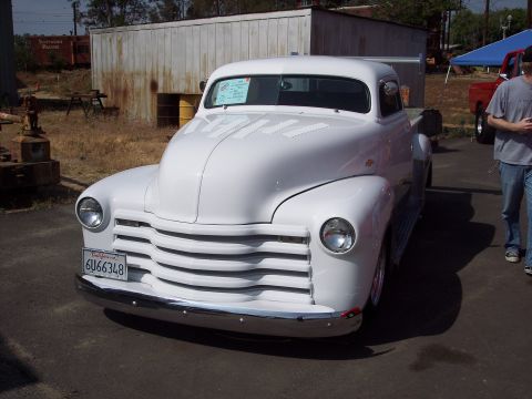 1981 Kenworth W900A - A classic white pickup truck is parked outdoors, with a person walking by in the background.