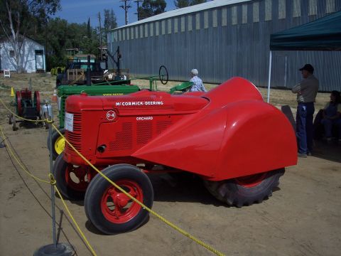 1981 Kenworth W900A - A red McCormick-Deering tractor, modified with a red aerodynamic fairing, is displayed alongside other farm equipment.