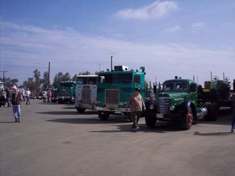 1981 Kenworth W900A - A collection of vintage trucks are displayed outdoors under a partly cloudy sky.
