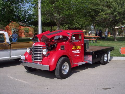 1981 Kenworth W900A - A red flatbed truck with its hood open is parked next to another vehicle at an outdoor event.
