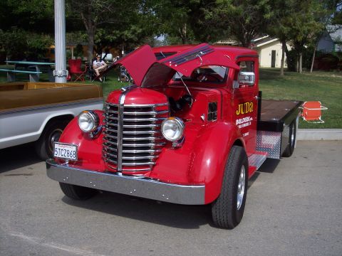 1981 Kenworth W900A - A red flatbed truck with its hood open is parked outdoors, displaying "JUDA BUILDERS" on its door.