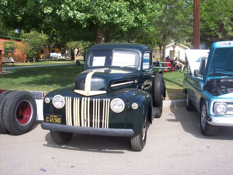 1981 Kenworth W900A - This 1940s Ford pickup truck is parked next to a blue pickup at an outdoor event.