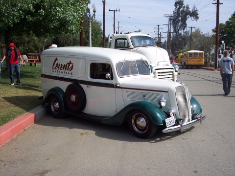 1981 Kenworth W900A - A vintage panel van is parked next to a larger truck, with a yellow school bus in the background.