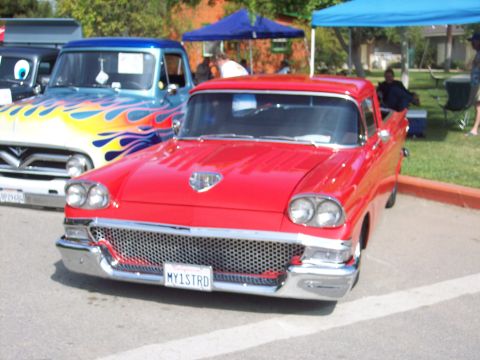 1981 Kenworth W900A - A red 1958 Ford Fairlane 500 Skyliner is parked next to a blue truck with flames.