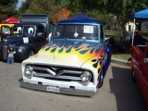 1981 Kenworth W900A - A custom pickup truck with a vibrant flame paint job is displayed at an outdoor event.