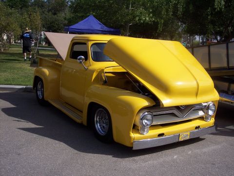 1981 Kenworth W900A - A yellow 1956 Ford F-series pickup truck is displayed with its hood open at an outdoor event.