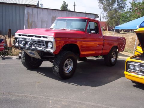 1981 Kenworth W900A - A red Ford pickup truck with off-road modifications is parked next to another vehicle.