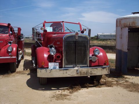 1981 Kenworth W900A - A red fire truck is parked next to another vehicle, with a building and distant train cars in the background.