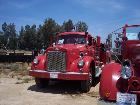 1981 Kenworth W900A - Two red fire trucks parked outdoors under a clear blue sky.