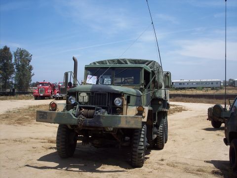 1981 Kenworth W900A - A military truck with a winch and antenna is parked on a dirt lot under a clear blue sky.