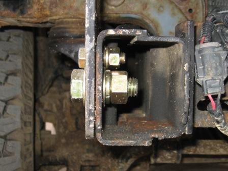 1993 Ford Bronco - Detail of a vehicle's frame and bumper mounting hardware, showing rust and bolted components.