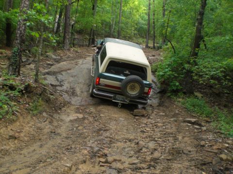 1989 Ford Bronco - This 1989 Ford Bronco navigates a challenging rocky and muddy trail through a dense forest.