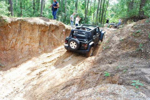 2008 Jeep Wrangler - A black Jeep Wrangler navigates a challenging dirt trail with spectators observing the off-road action.