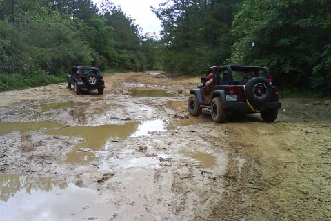 2008 Jeep Wrangler - Two Jeep Wranglers navigate a challenging muddy trail, kicking up dirt and water.
