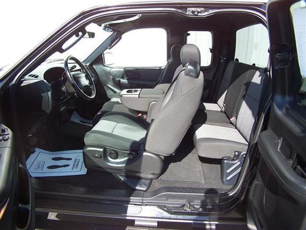 Interior view of a truck with front bucket seats and a rear bench seat. Floor mats are visible