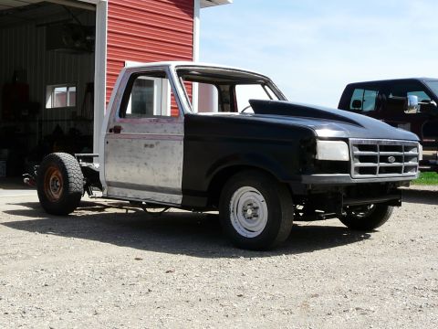 1994 Ford F-150 - This 1994 Ford F-150 is in a state of unfinished repair, a prominent black hood scoop and a mix of bare metal and black body panels.