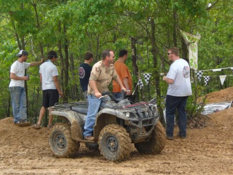 1989 Ford Bronco - An ATV navigates a muddy track with spectators observing the event.