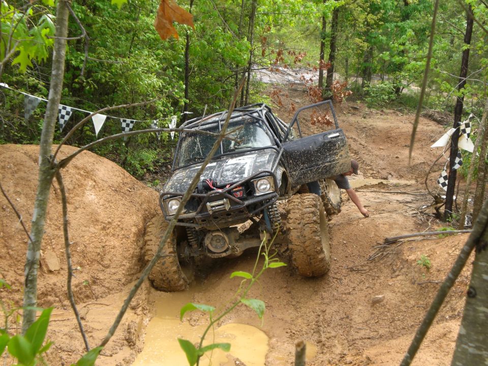 Off-road vehicle with roll cage stuck in mud, driver's door open