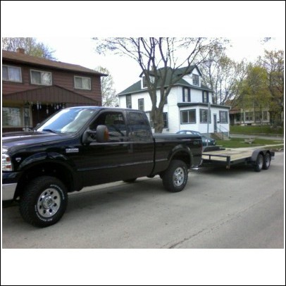 2005 Ford F-250 - Black 2005 Ford F-250 Super Duty pickup truck is seen from the side, towing a trailer.