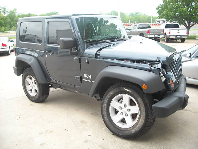 Dark gray Jeep Wrangler with hood open and front end damage