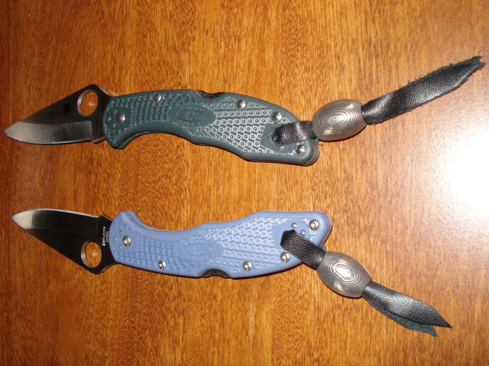 Two folding knives, one green and one blue, with decorative lanyards