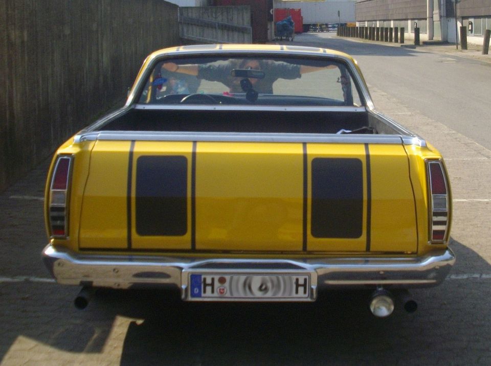 Yellow 1971 Ford Ranchero pickup truck rear view with black stripes on tailgate