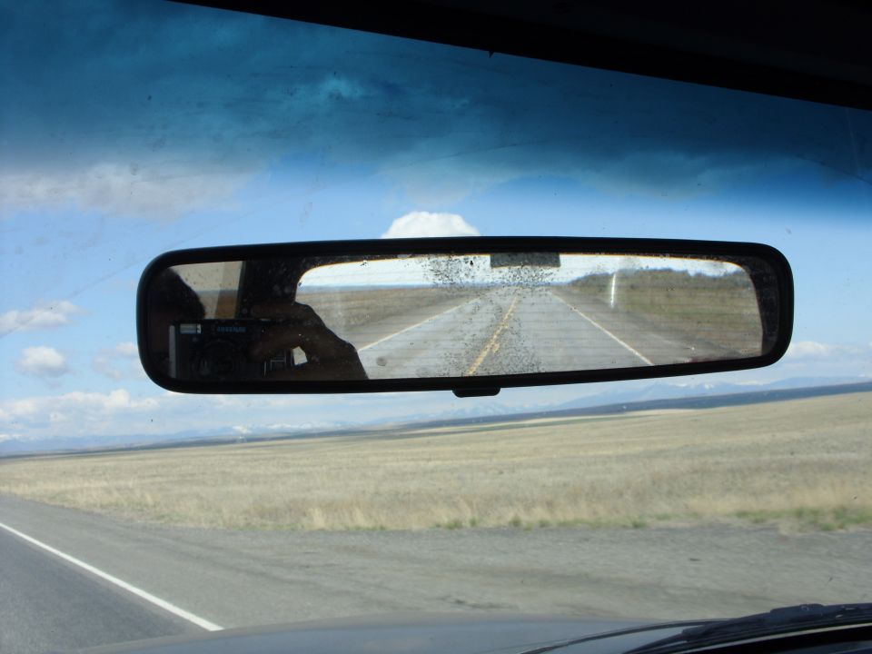 Interior rearview mirror reflection showing a road stretching into the distance