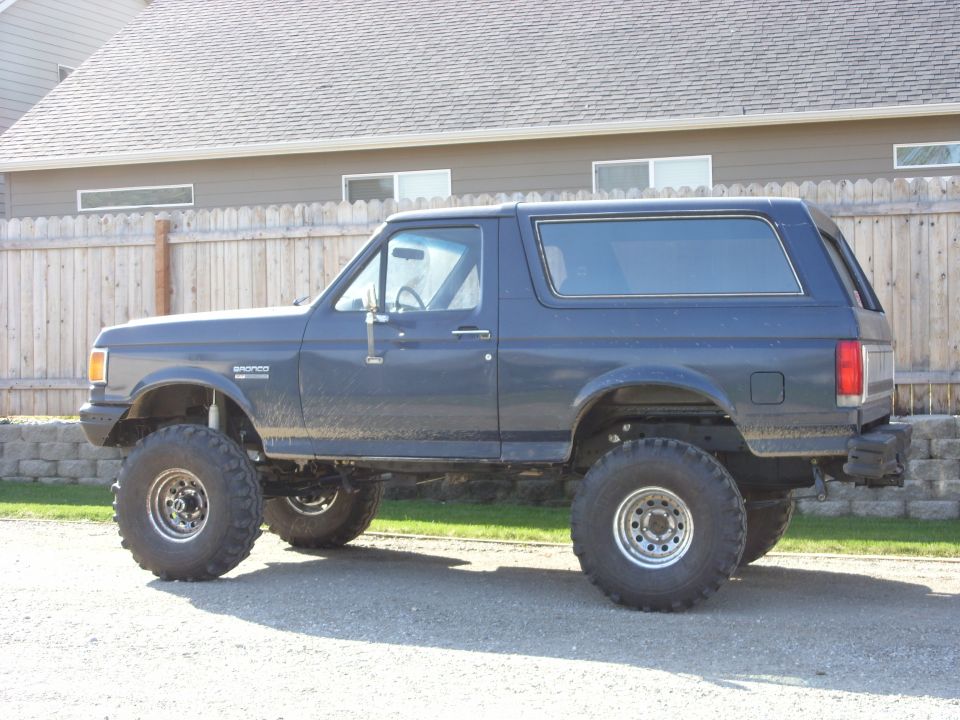 Dark blue SUV with lifted suspension and large off-road tires, seen from the side