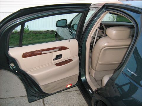 1988 Mercury Grand Marquis - The interior of a green sedan shows tan leather seats and wood trim on the door panel.