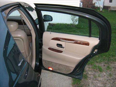 1988 Mercury Grand Marquis - Interior view of a dark green car, showing the tan door panel with wood accents and beige leather seats.