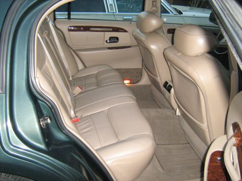 1988 Mercury Grand Marquis - The interior of a green sedan shows tan leather seats and wood trim. Another vehicle is visible outside.