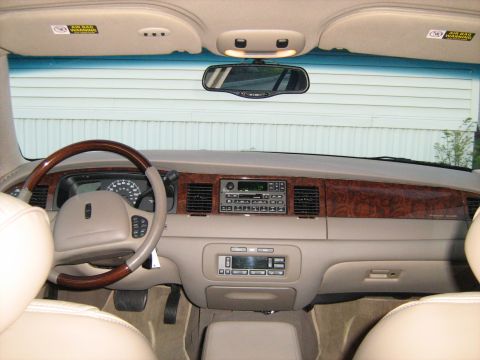 1988 Mercury Grand Marquis - The interior of a 2001 Lincoln Town Car shows a wood-trimmed dashboard and beige leather seats.