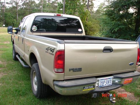 1987 Ford Bronco - This gold Ford F-250 Super Duty pickup truck is shown from the rear 3/4 angle.