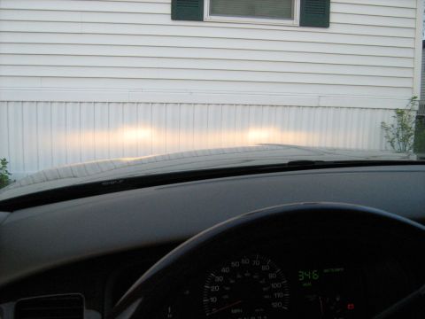 1988 Mercury Grand Marquis - The dashboard and headlights of a car are visible, with a white building in the background.