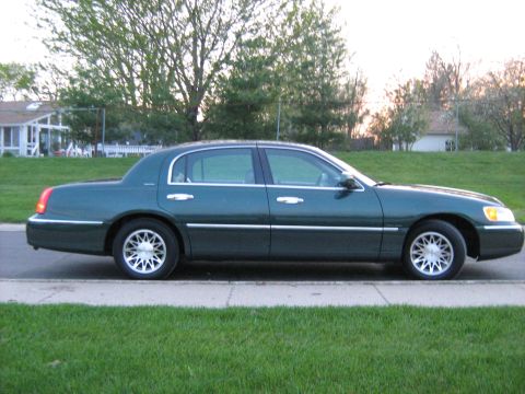 1988 Mercury Grand Marquis - A dark green Lincoln Town Car is seen from the side, parked next to a grassy area.