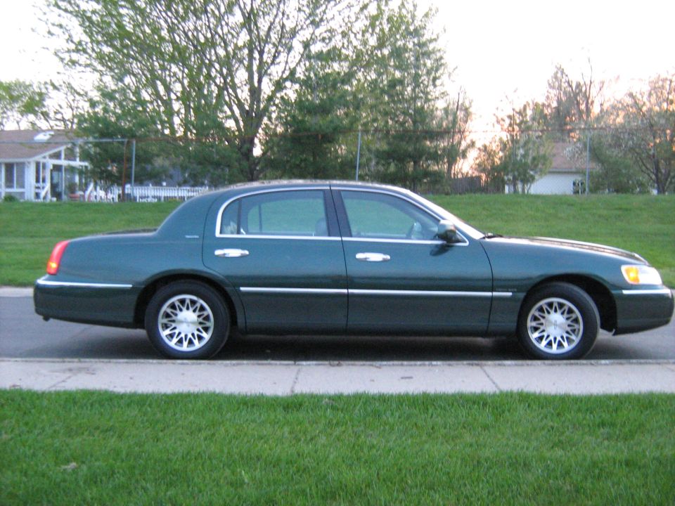 Green Lincoln Town Car parked on a curb, side view