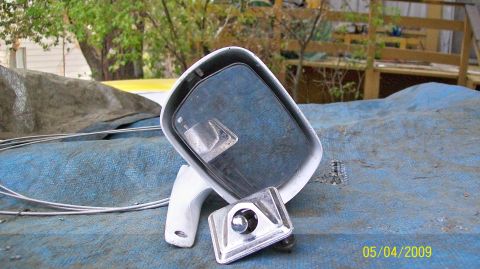 1972 Ford Ranchero - A disassembled car side mirror assembly sits on a blue tarp outdoors, with trees and a wooden structure in the background.