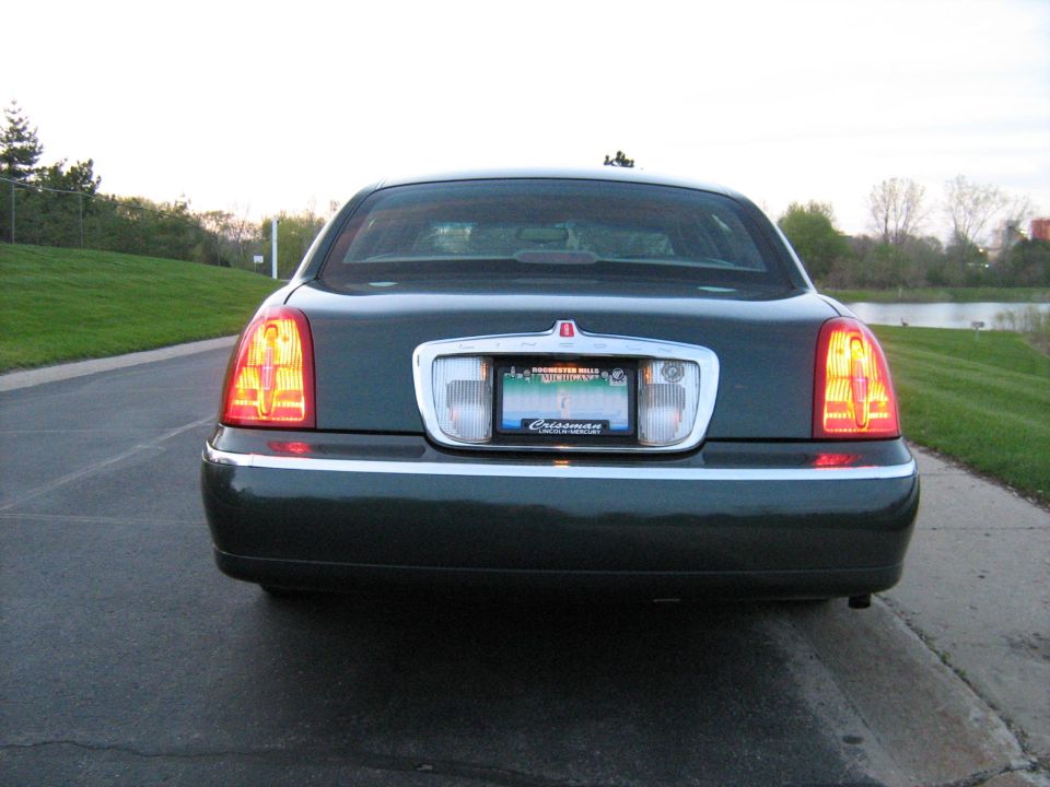 Dark green Lincoln Town Car rear view with taillights lit and Michigan plate