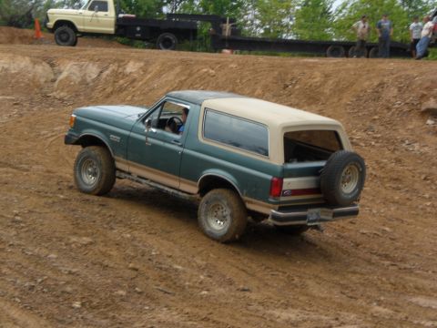 1989 Ford Bronco - This 1989 Ford Bronco navigates a challenging dirt terrain, with another truck and trailer visible in the background.