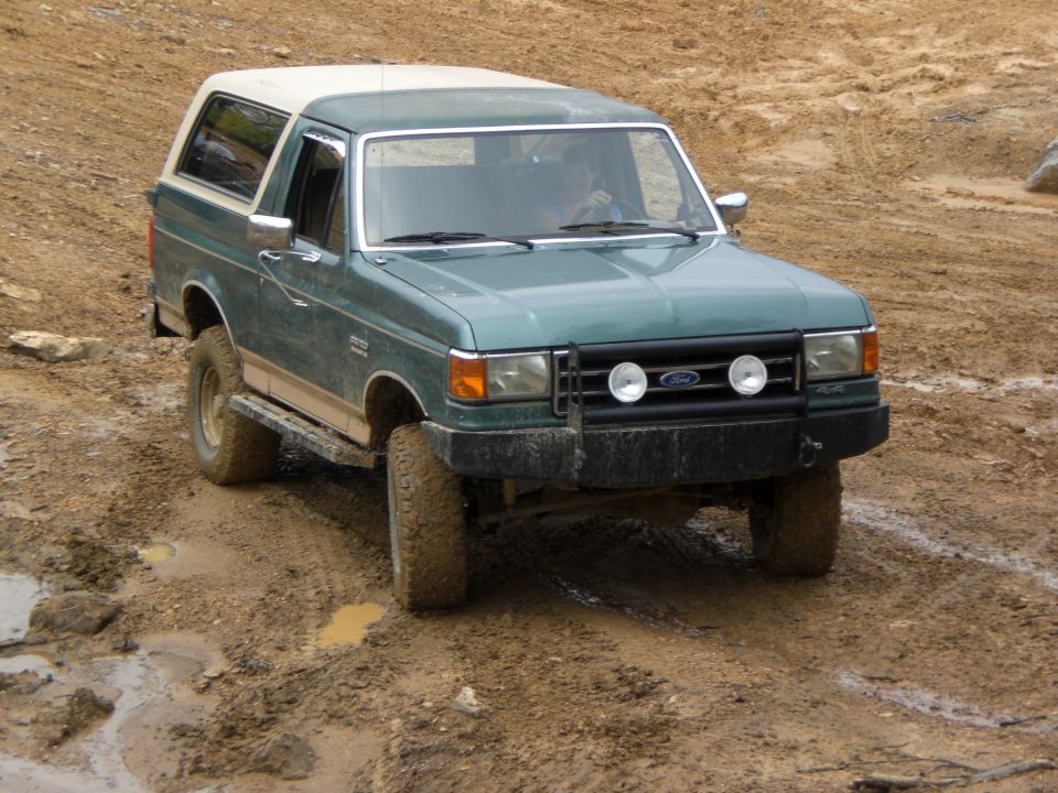 1989 Ford Bronco on a muddy off-road trail, front view