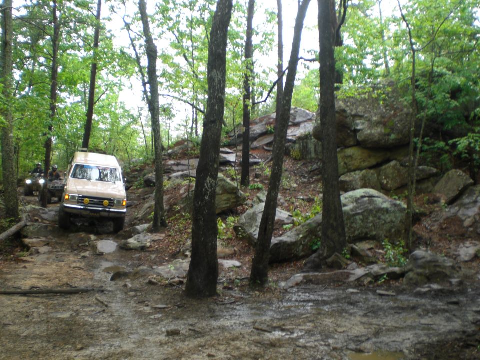 Tan van and ATV on rocky forest trail