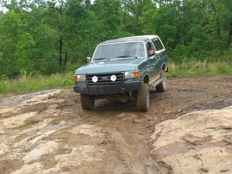 Green SUV with white roof on muddy trail. 1987 model year