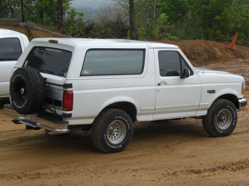 White Ford Bronco with spare tire on rear, parked on dirt road