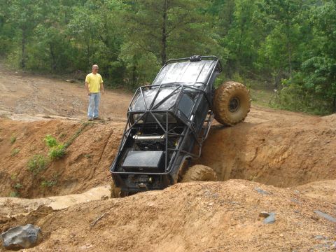 1989 Ford Bronco - A heavily modified off-road vehicle with a prominent roll cage navigates a challenging muddy terrain.