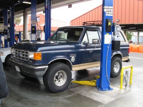 1986 Ford Bronco - A blue Ford Bronco is shown on a car lift in a service bay.