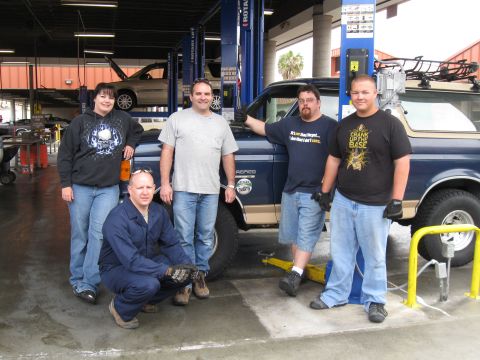1986 Ford Bronco - A group of people stand with a blue 1986 Ford Bronco in a garage setting.