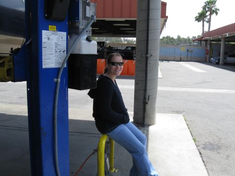 1986 Ford Bronco - A woman waits next to a car lift in an outdoor service area.