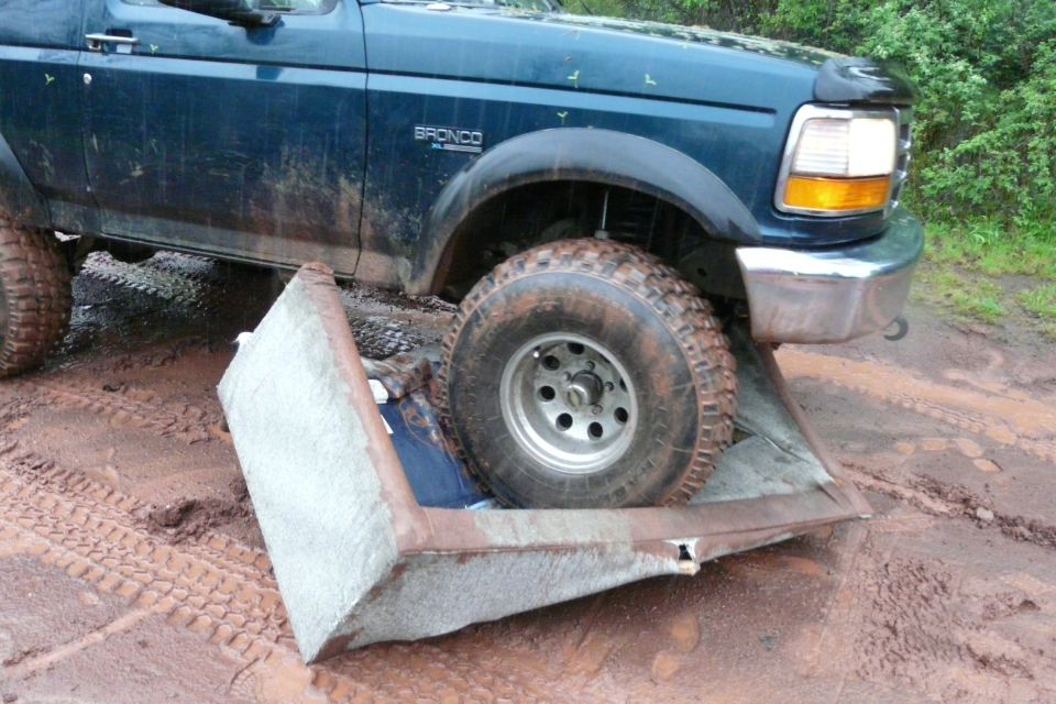 1995 Ford Bronco front passenger side tire on a couch cushion in mud