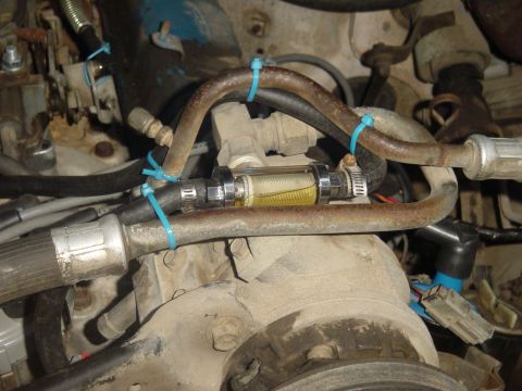 1982 Ford Bronco - Inline fuel filter installed in the engine bay, showing fuel flow through the clear housing.