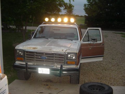 1982 Ford Bronco - This 1980s Ford Bronco has a light bar mounted on its roof and the driver's door is open.